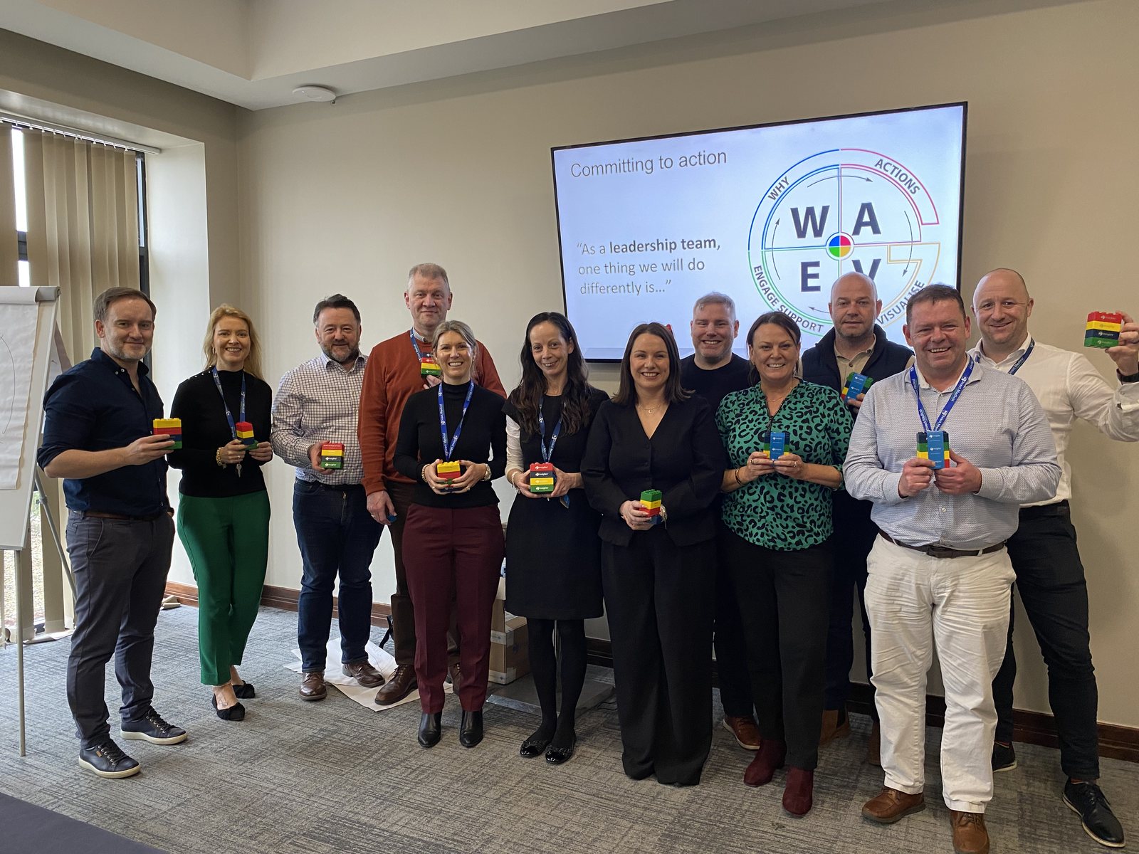 A leadership team at a workshop, holding their Insights Discovery colour blocks