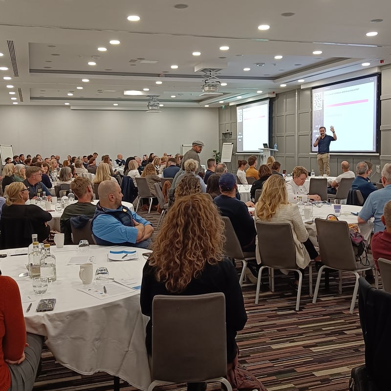 David O'Grady facilitating a full room of leaders, presenting live polling results on screen